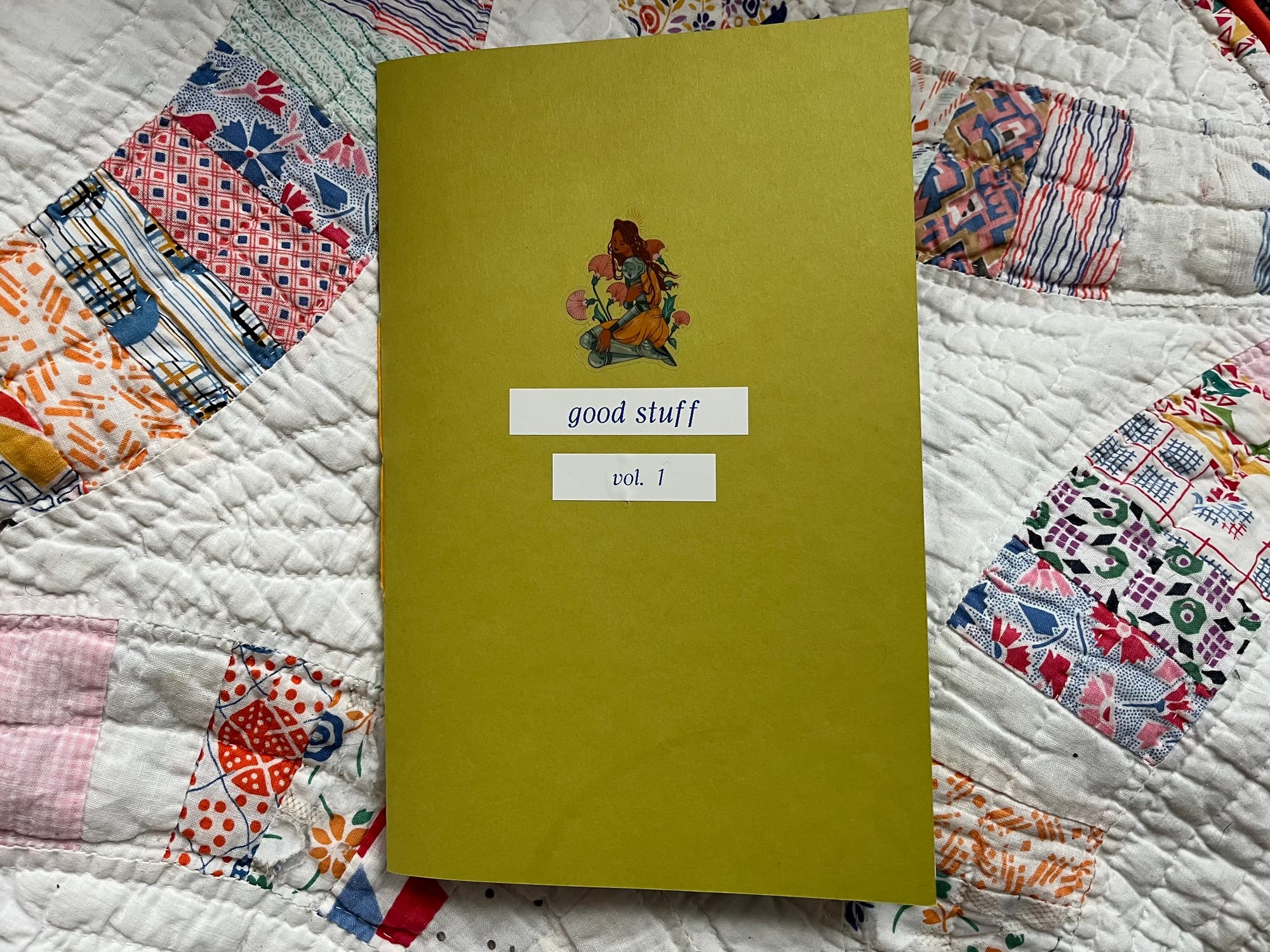 photo of a zine with a chartreuse cardstock cover. there's a sticker of a lady knight on it and the words "good stuff vol. 1" underneath